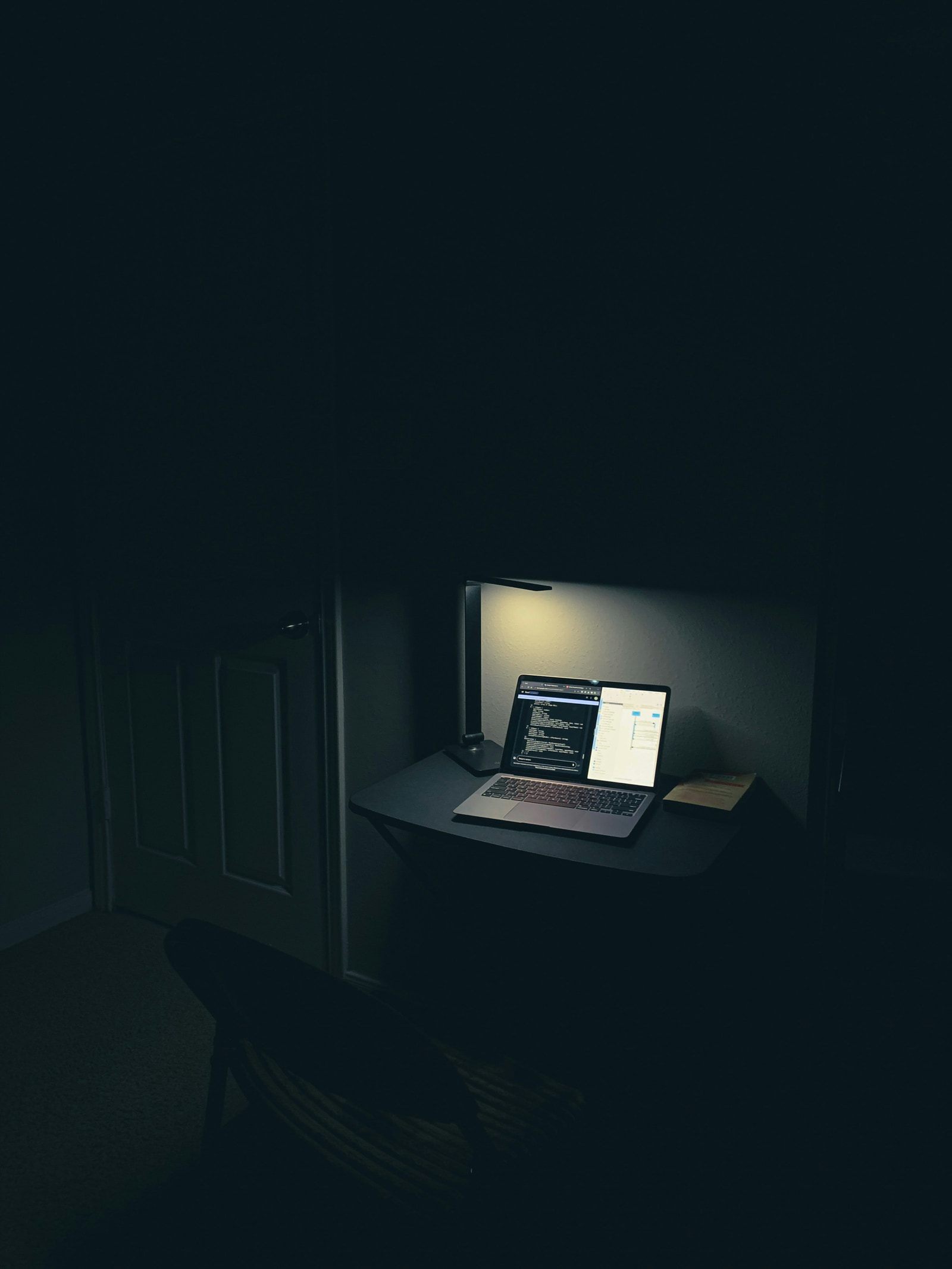 A laptop lit in a dark room at night