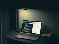 A laptop lit in a dark room at night